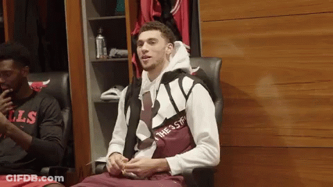 A Man In A Chicago Bulls Shirt Sits In A Chair In A Locker Room GIF