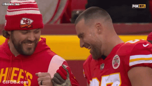 A Man In A Chiefs Shirt Laughs With Another Man GIF