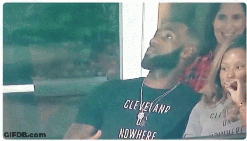 A Man In A Cleveland T-Shirt Is Sitting In A Stadium With A Woman And A Child . GIF