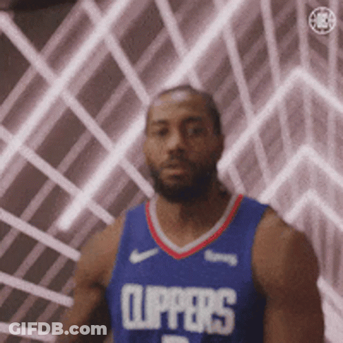 A Man In A Clippers Jersey Is Standing In Front Of A Wall With Lights Behind Him . GIF