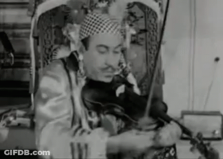 A Man In A Clown Costume Is Playing A Violin . GIF