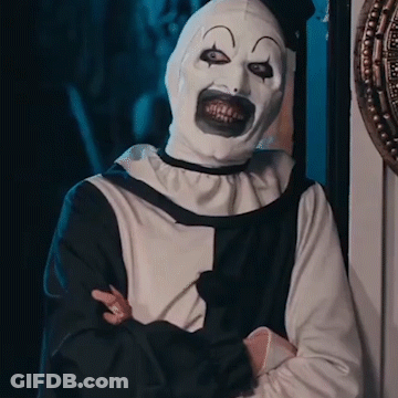 A Man In A Clown Costume Is Standing With His Arms Crossed . GIF