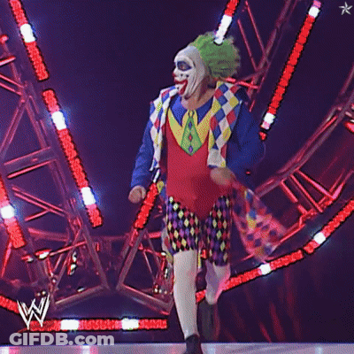 A Man In A Clown Costume Is Walking On A Stage GIF