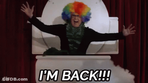 A Man In A Clown Wig Is Sitting In A Toilet With His Arms Outstretched And The Words I 'M Back GIF