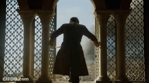 A Man In A Coat Is Standing In Front Of A Window With Columns GIF