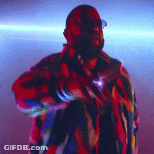A Man In A Colorful Jacket Is Dancing In A Dark Room GIF