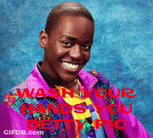 A Man In A Colorful Jacket Is Smiling With The Words " Wash Your Hands You Deity Pic " Behind Him GIF