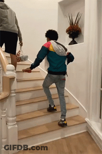 A Man In A Colorful Jacket Is Walking Down Stairs GIF