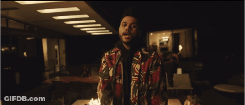A Man In A Colorful Jacket Stands In Front Of A Table Full Of Candles GIF