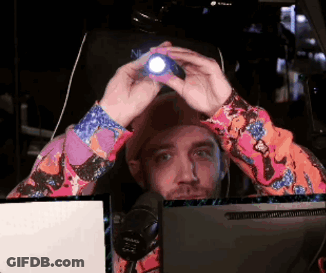 A Man In A Colorful Shirt Is Holding A Flashlight In Front Of His Head GIF