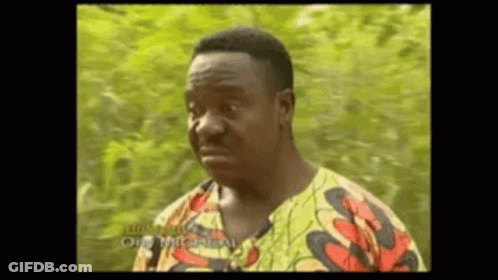 A Man In A Colorful Shirt Is Making A Funny Face While Standing In Front Of A Tree . GIF