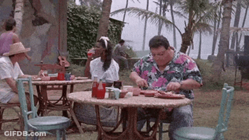 A Man In A Colorful Shirt Is Sitting At A Table Eating GIF
