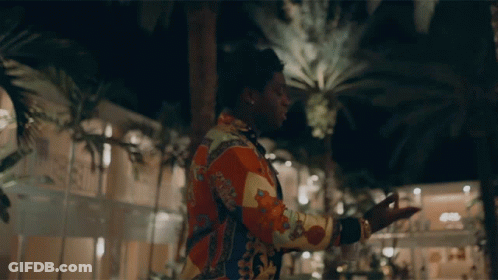 A Man In A Colorful Shirt With The Word Gucci On The Back GIF