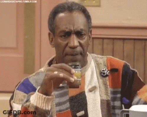 A Man In A Colorful Sweater Is Holding A Small Jar Of Something In His Hand . GIF