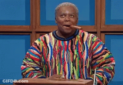 A Man In A Colorful Sweater Is Standing At A Podium And Pointing At Something . GIF