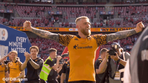 A Man In A Corwudun Jersey Stands In Front Of A Sign That Says " Every Minute Matters " GIF