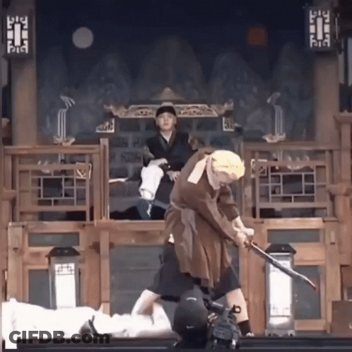 A Man In A Costume Is Holding A Sword While Another Man Watches GIF