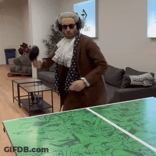A Man In A Costume Is Playing Ping Pong With A Green Table GIF