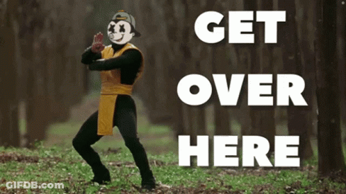 A Man In A Costume Is Standing In The Woods With The Words Get Over Here Behind Him GIF