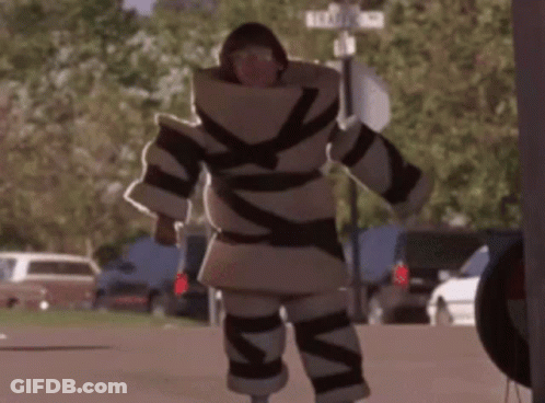 A Man In A Costume Is Walking Down A Street With A Sign That Says Elizabeth St. GIF