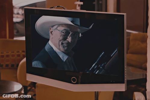 A Man In A Cowboy Hat And Glasses Is On A Television Screen GIF