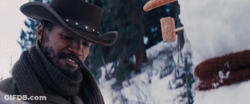 A Man In A Cowboy Hat And Scarf Is Standing In The Snow Looking At Something GIF