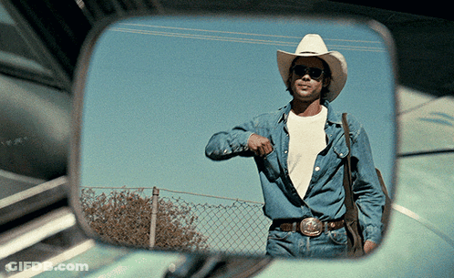 A Man In A Cowboy Hat And Sunglasses Is Reflected In A Car Mirror GIF