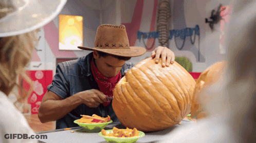 A Man In A Cowboy Hat Carves A Pumpkin GIF