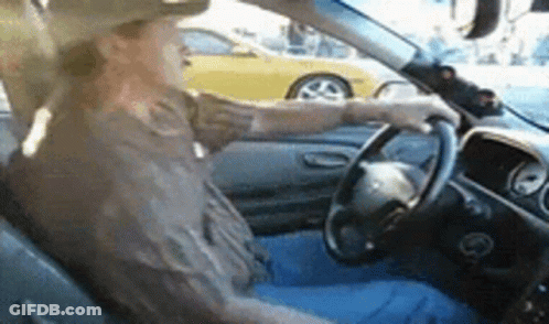A Man In A Cowboy Hat Is Driving A Car With A Yellow Car In The Background . GIF