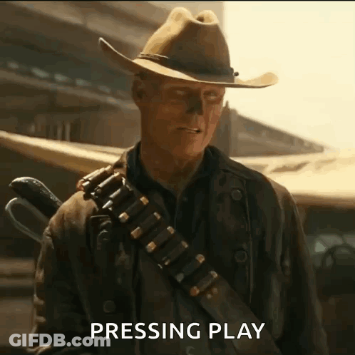 A Man In A Cowboy Hat Is Holding A Gun And Pressing Play GIF