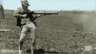 A Man In A Cowboy Hat Is Holding A Large Rifle In A Field GIF