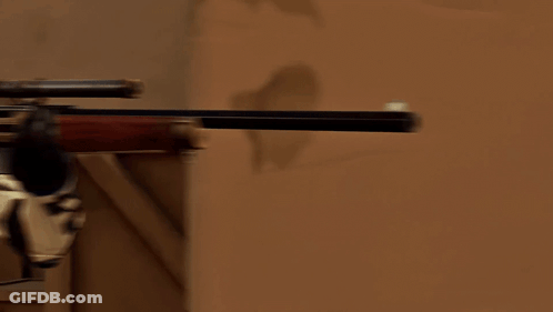 A Man In A Cowboy Hat Is Holding A Rifle In His Right Hand GIF