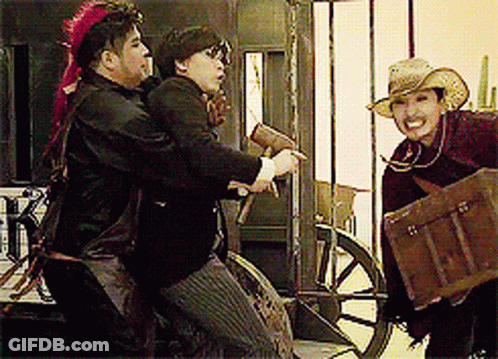 A Man In A Cowboy Hat Is Holding A Trunk And Talking To Two Other Men GIF