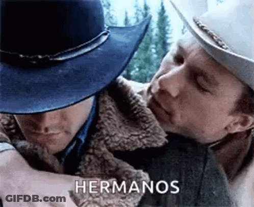A Man In A Cowboy Hat Is Hugging Another Man In A Jacket . GIF