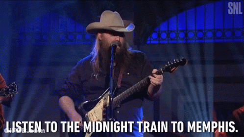 A Man In A Cowboy Hat Is Playing A Guitar And Singing Into A Microphone GIF