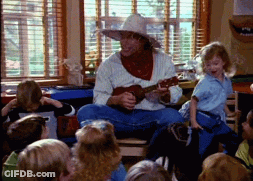 A Man In A Cowboy Hat Is Playing A Guitar In Front Of Children GIF