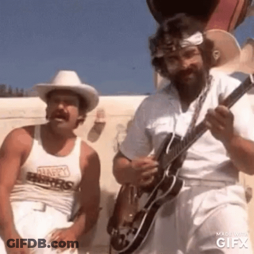 A Man In A Cowboy Hat Is Playing A Guitar Next To Another Man In White Pants . GIF