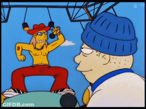 A Man In A Cowboy Hat Is Singing Into A Microphone While Another Man Watches GIF