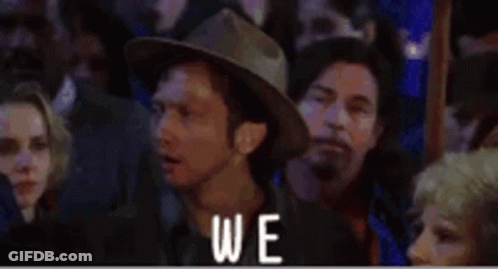 A Man In A Cowboy Hat Is Sitting In A Crowd Of People With The Word Again Written Above Him . GIF