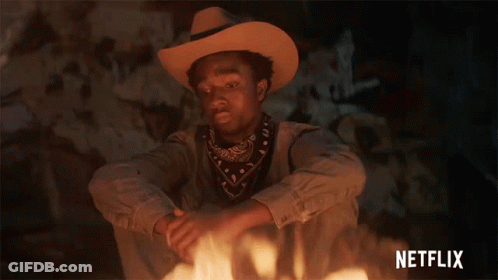 A Man In A Cowboy Hat Is Sitting In Front Of A Fire With Netflix Written In The Corner GIF