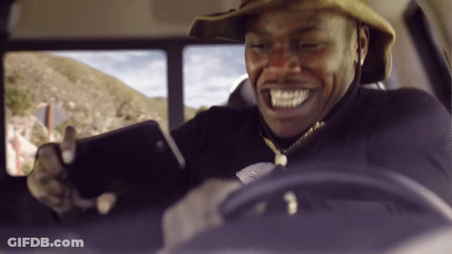 A Man In A Cowboy Hat Is Smiling While Looking At His Cell Phone GIF