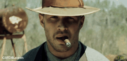 A Man In A Cowboy Hat Is Smoking A Cigar With The Letters Thw Below Him GIF