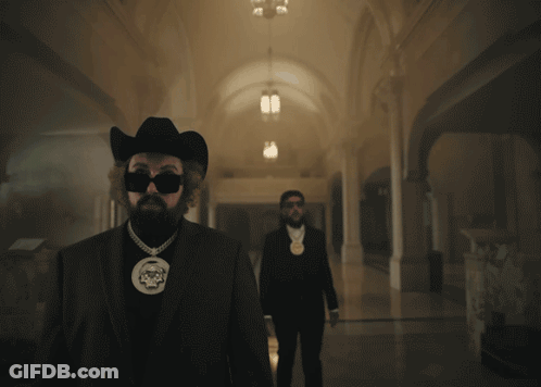 A Man In A Cowboy Hat Is Smoking A Cigarette GIF