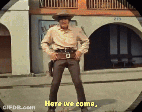 A Man In A Cowboy Hat Is Standing In Front Of A Building That Says 213 On It GIF