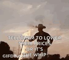 A Man In A Cowboy Hat Is Standing In Front Of A Fire Holding A Whip . GIF