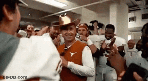 A Man In A Cowboy Hat Is Standing In Front Of A Group Of People . GIF