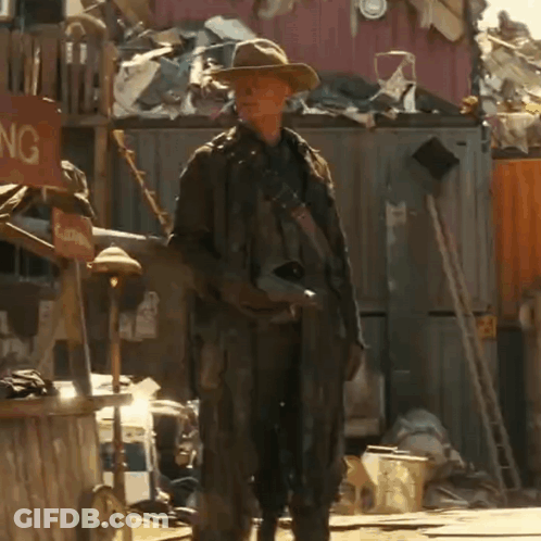 A Man In A Cowboy Hat Is Standing In Front Of A Sign That Says Clothing GIF