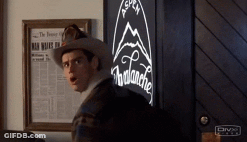 A Man In A Cowboy Hat Is Standing In Front Of A Vending Machine With A Mountain On It . GIF