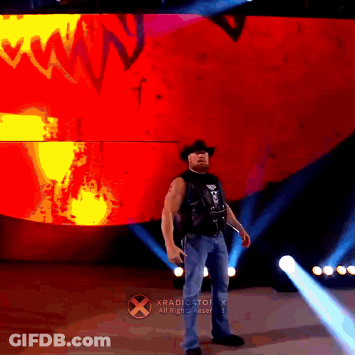 A Man In A Cowboy Hat Is Standing In Front Of A Xradicator X Sign GIF