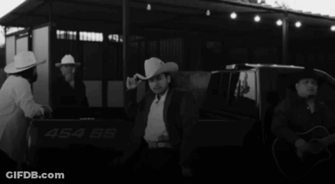 A Man In A Cowboy Hat Is Standing In The Back Of A Truck With The Number 454 On It GIF